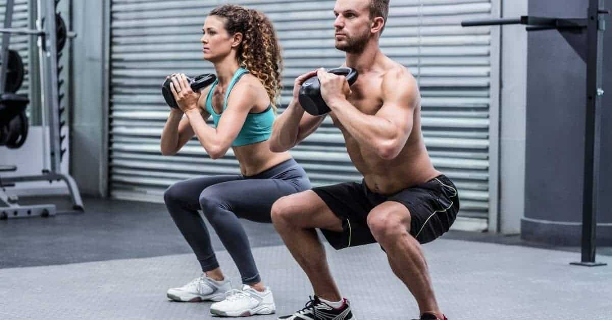 Two people doing weighted squats in an exercise room.